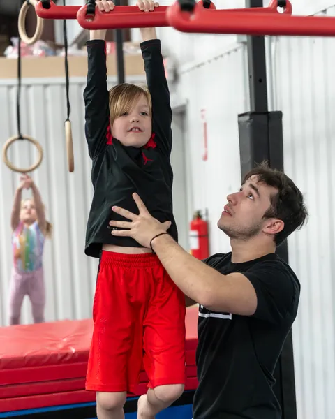 Young ninja conquering rope climb obstacle with determination and focus