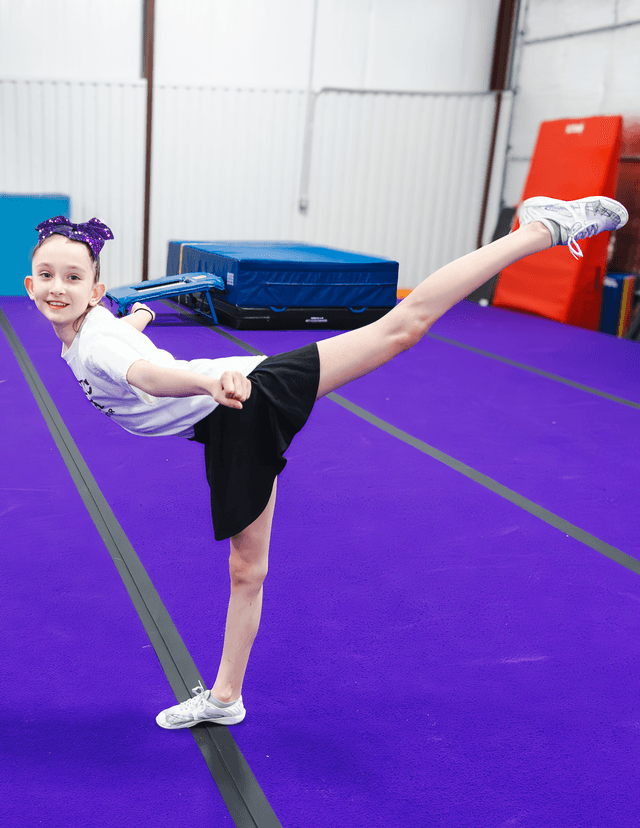 Cheerleader holding a high kick on the purple spring floor