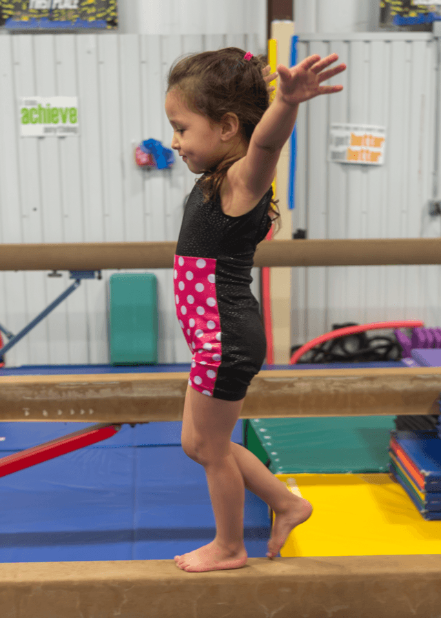 Preschooler walking the low beam with arms out at Majestic in Willis, TX