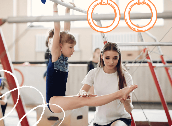 A Majestic coach spotting a young gymnast on the bars during a class